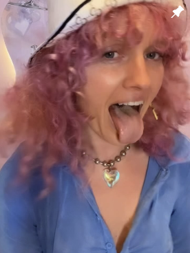 Teddi with pink curls and a heart necklace, tongue out