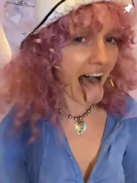 Teddi with pink curls and a heart necklace, tongue out